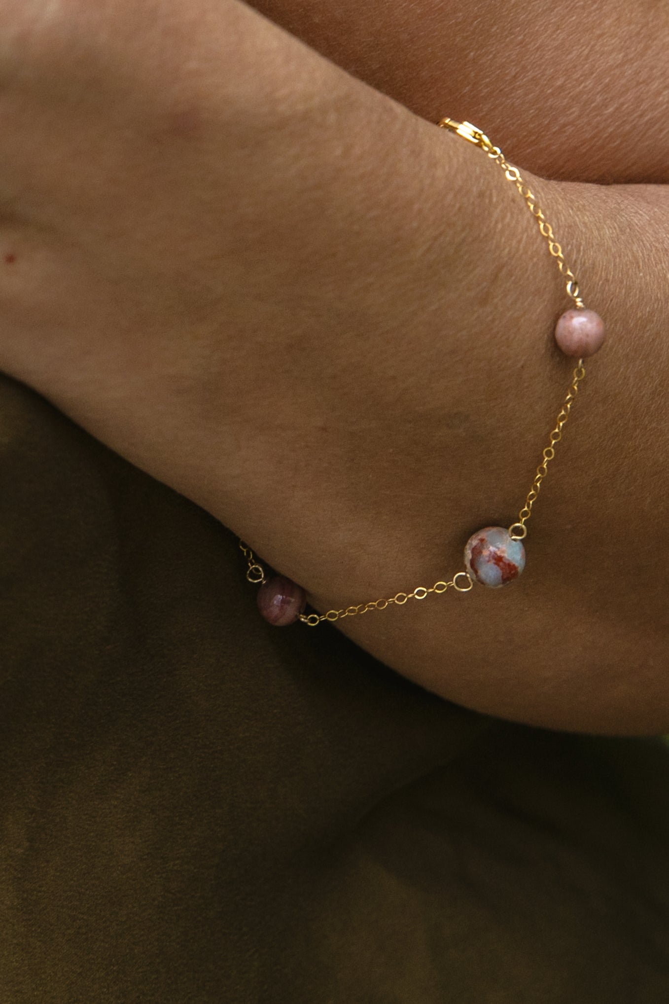 A delicate handcrafted gold-filled chain bracelet with gemstones, shown worn on a person's wrist.