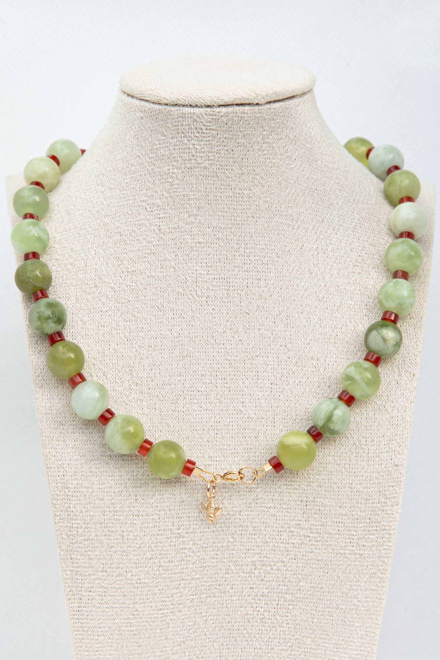 Beautiful necklace set with green serpentine and red carnelian gemstones with a dangling golden bee charm. 