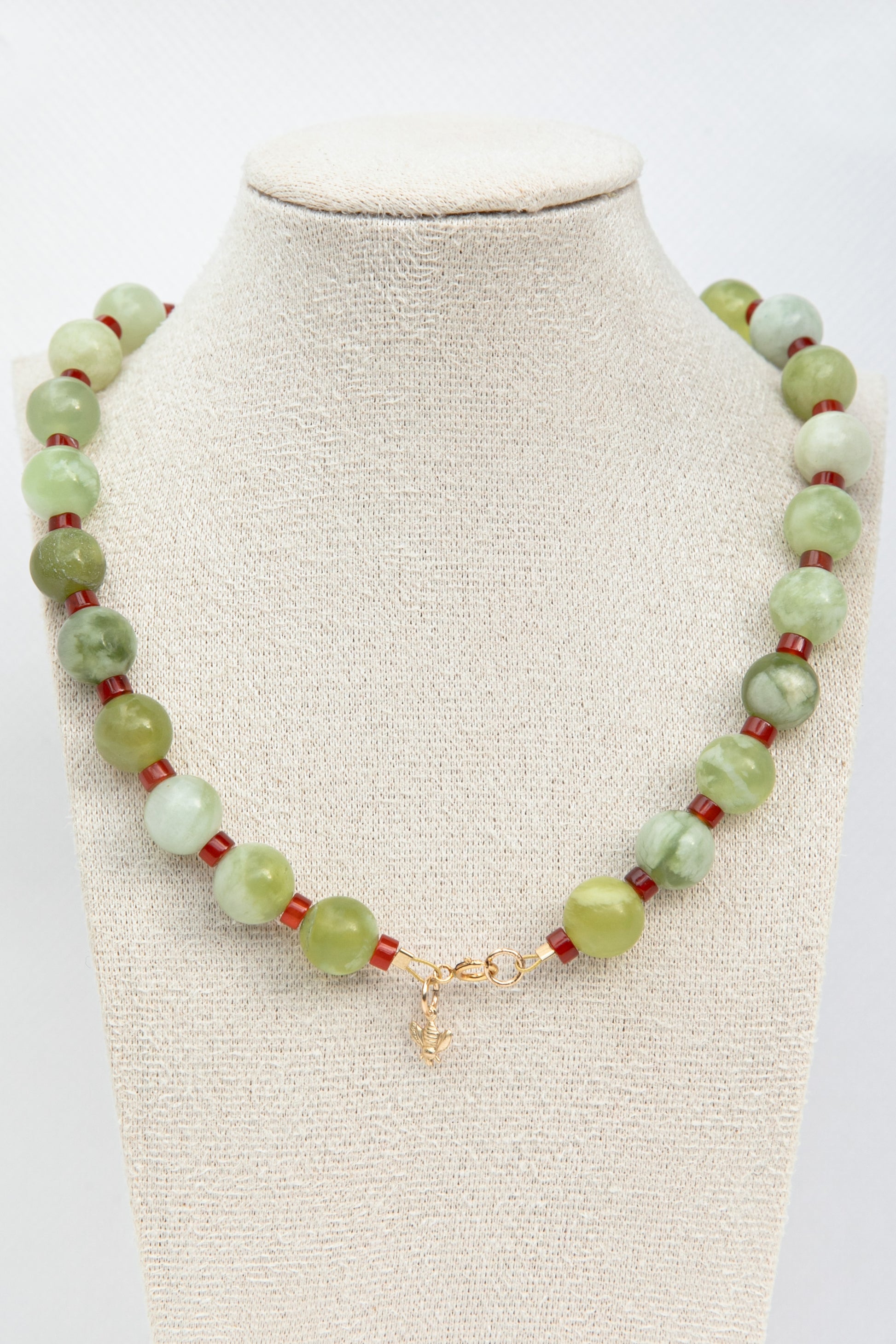 Beautiful necklace set with green serpentine and red carnelian gemstones with a dangling golden bee charm. 