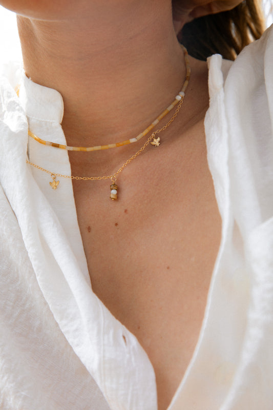 Close-up of a person wearing gold and honey handmade necklace. Fine gold-filled chain and natural yellow aventurine with little bees.  