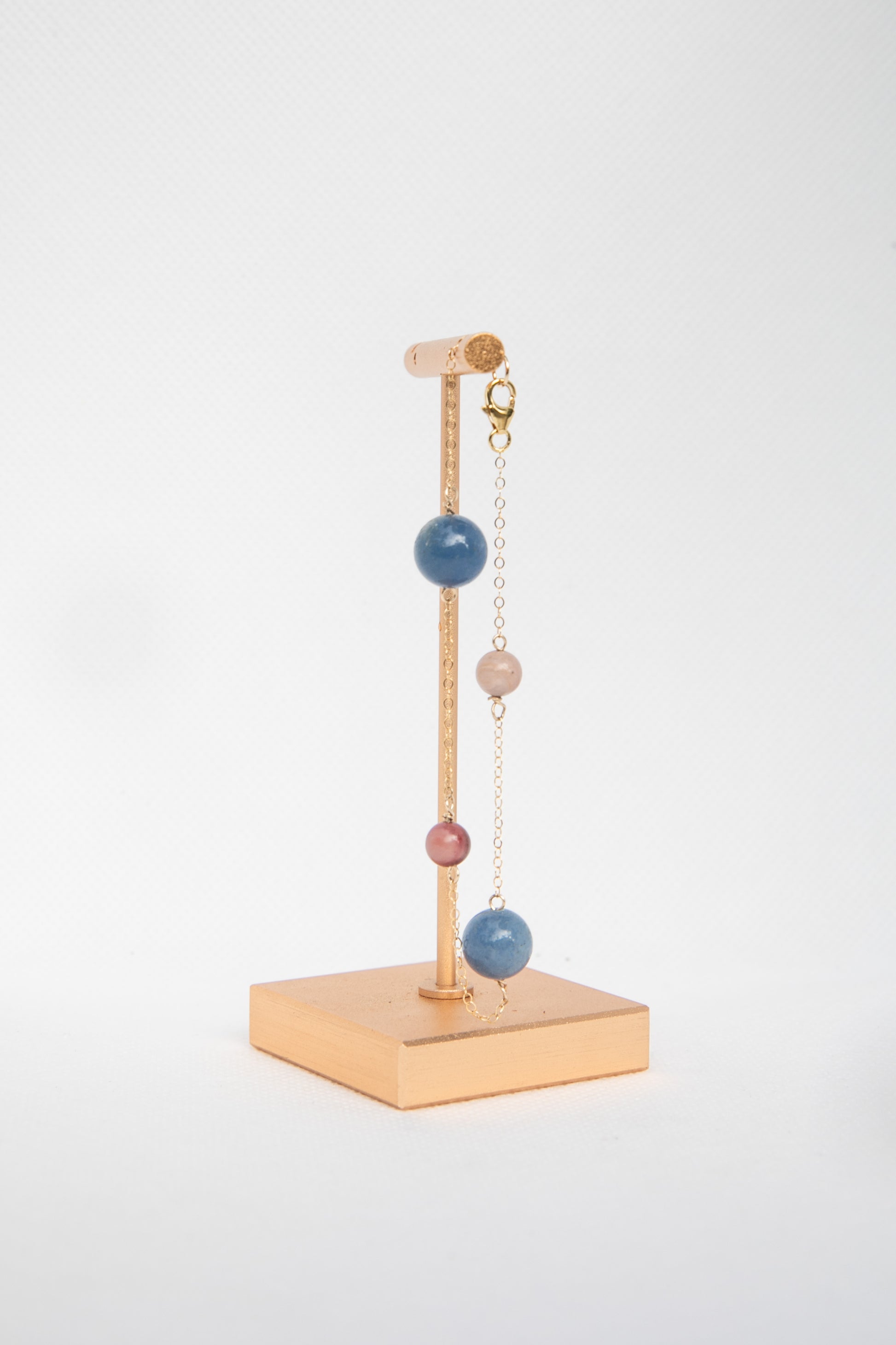 Delicate handmade bracelet on a stand with colorful semi-precious stones. 