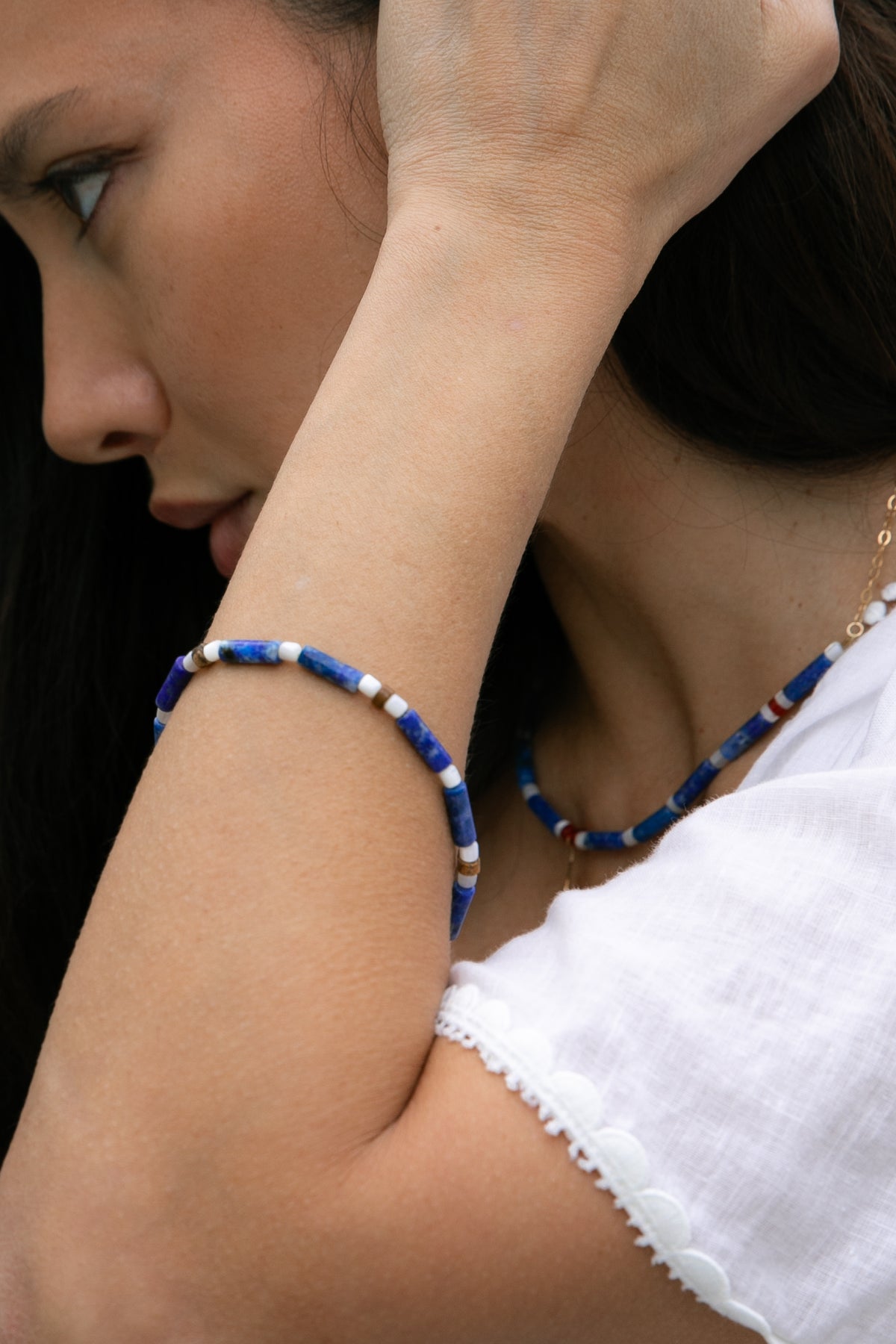 Close-up of a woman wearing a handmade bracelet with lapis lazuli, white mother of pearl and natural picture jasper. Jewellry inspired by the colours and traditions of the Mediterranean. 